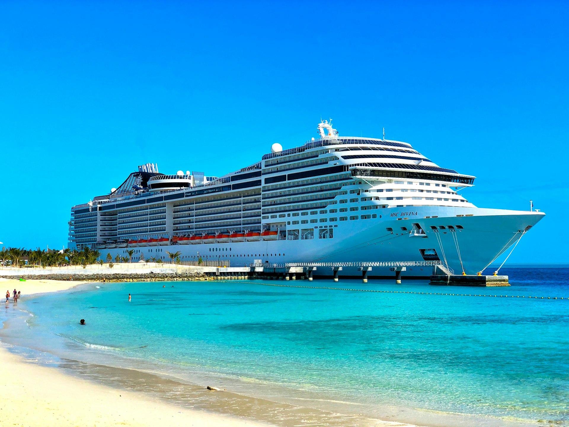 Cruise ship docked at a tropical beach with clear blue sky