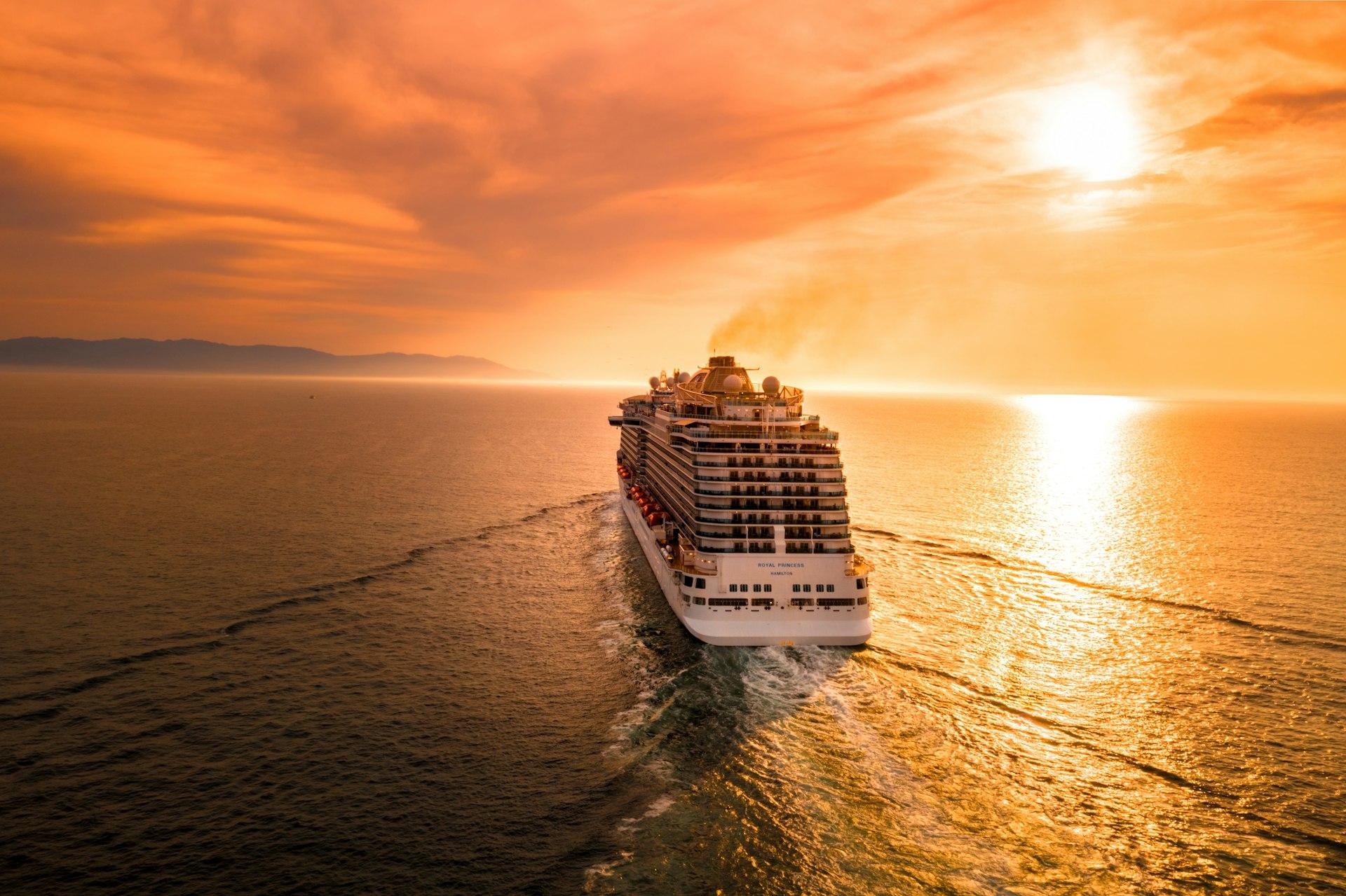 Cruise ship sailing into a golden sunset